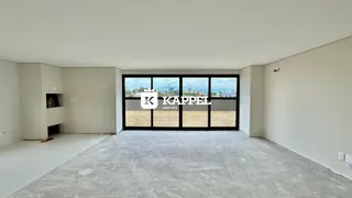 Sala ampla com piso de concreto e grandes janelas que dão vista para o exterior.