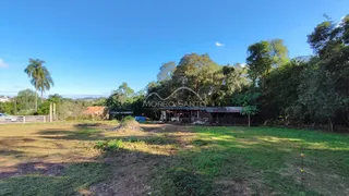 Vista externa de uma propriedade com área gramada e vegetação densa ao fundo.