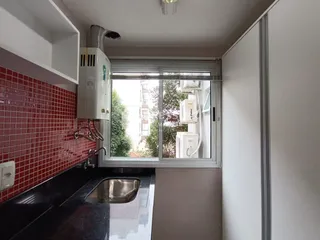 Interior da cozinha com revestimento de azulejos vermelhos e janela.