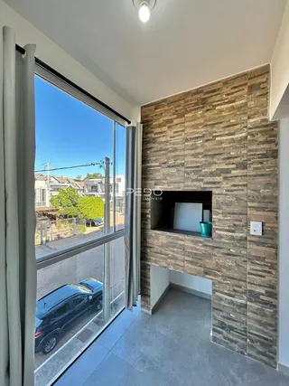 Vista interna de uma sala com parede de pedra e grande janela.