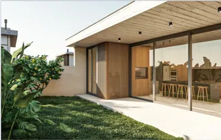 Exterior da casa com jardim verde e grandes portas de vidro.