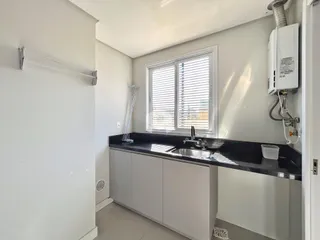 Foto de uma cozinha moderna com bancada escura e armários brancos.