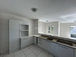 Vista da cozinha com armários brancos e piso cerâmico claro.
