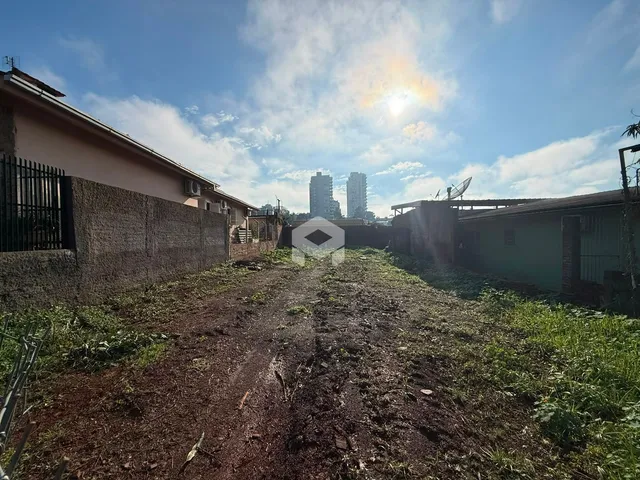 Vista externa de uma propriedade com muro e vegetação no primeiro plano.