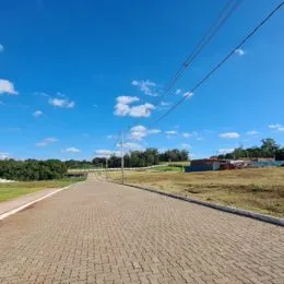 Uma estrada pavimentada se estende por uma área gramada sob um céu azul.