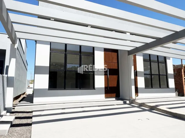 Fachada moderna de uma residência com estrutura branca e janelas escuras.