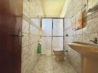 Foto de um banheiro com revestimento de azulejos claros e um vaso sanitário.
