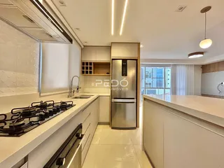 Vista da cozinha moderna com armários brancos e bancadas claras.