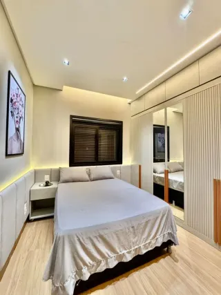 Foto de um quarto com cama e piso de madeira clara.