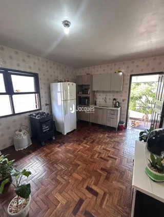 Foto interna de uma cozinha com piso de madeira e armários brancos.