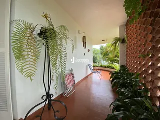 Vista interna de um corredor com piso de terracota e plantas decorativas.