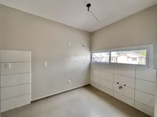 Interior de uma sala com paredes brancas e piso claro.