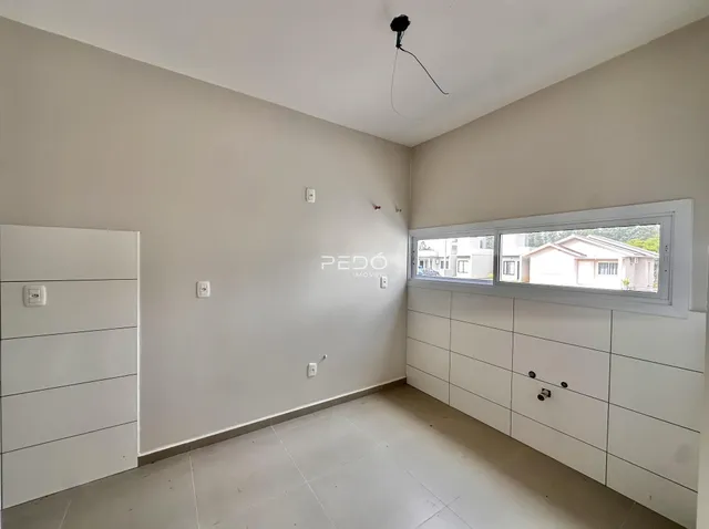 Interior de uma sala com paredes brancas e piso claro.