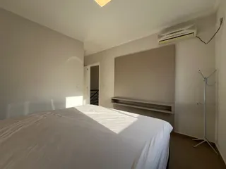 Quarto com cama grande e paredes brancas, com ar-condicionado instalado.