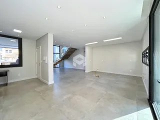 Uma ampla área comum com piso de concreto polido e pé direito alto.