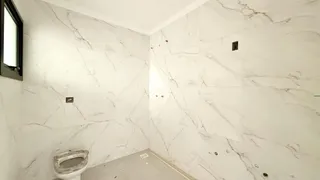 Foto da parede de um banheiro com acabamento em mármore branco.
