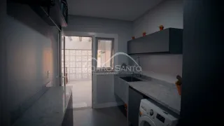 Cozinha moderna com armários escuros e piso claro em ambiente interno.