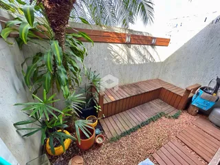 Vista externa de um jardim com vegetação densa e uma estrutura de madeira.
