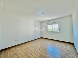 Ambiente interno de uma sala com piso de madeira clara e paredes brancas.