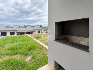 Vista externa de uma propriedade com jardim gramado e parede de alvenaria.