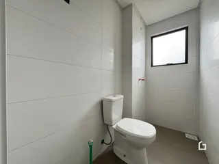 Foto de um banheiro interno com paredes brancas e piso neutro.
