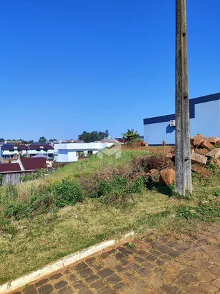 Vista externa de uma propriedade com terreno inclinado e vegetação.