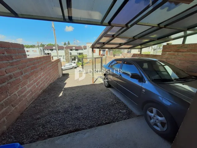 Vista externa de uma propriedade com muro de tijolos e área de estacionamento.