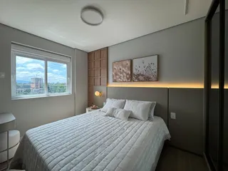Quarto com cama de casal e janela com vista para a paisagem.