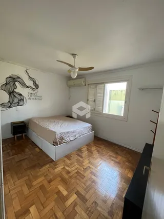 Quarto com piso de madeira e janela.