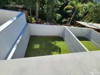 Vista de um jardim com grama artificial e paredes de concreto em uma propriedade em Lajeado.