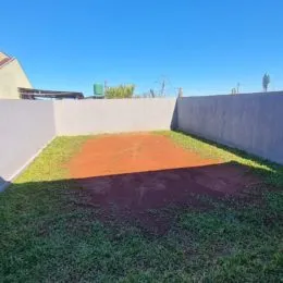 Vista externa mostrando um gramado e área de terra.