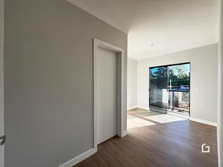 Interior de um corredor com piso de madeira e porta branca.