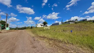 Vista da propriedade com estrada de terra e vegetação ao fundo.