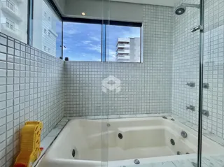 Banheiro com revestimento cerâmico branco e banheira.