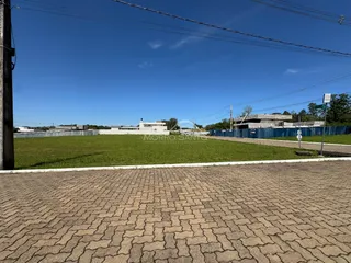 Vista externa de um terreno gramado com estruturas ao fundo.