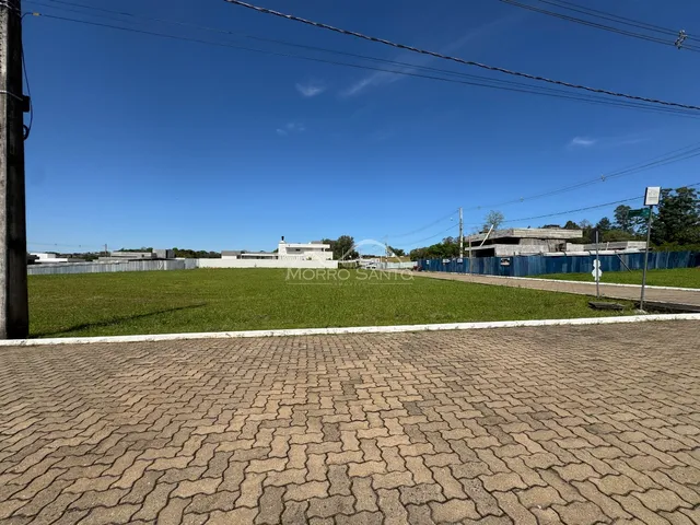 Vista externa de um terreno gramado com estruturas ao fundo.