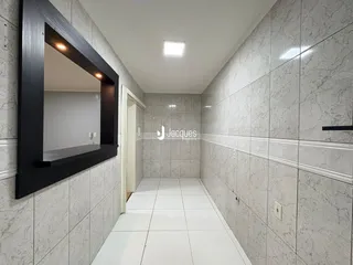 Vista de um corredor interno com revestimento de azulejos claros.