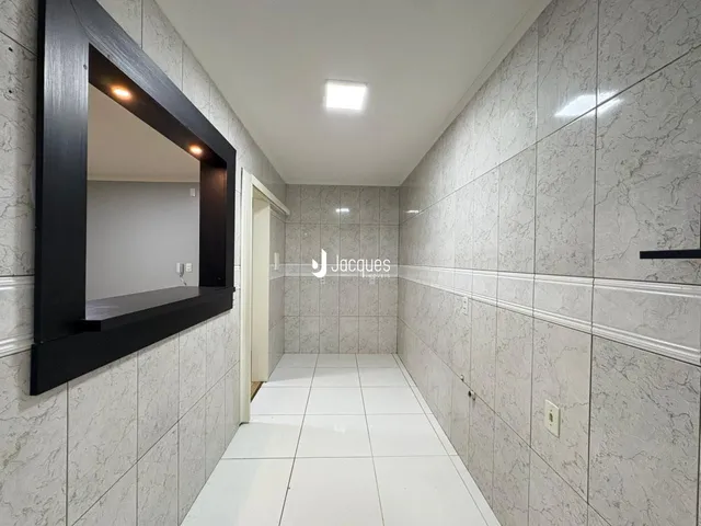 Vista de um corredor interno com revestimento de azulejos claros.