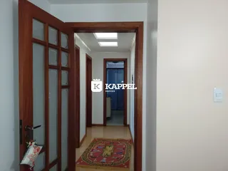Hall de entrada com piso de madeira e um tapete estampado.