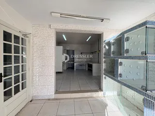 Interior de uma sala com revestimento de azulejos brancos e porta de vidro.