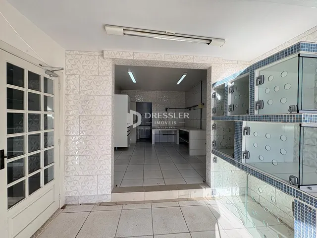 Interior de uma sala com revestimento de azulejos brancos e porta de vidro.