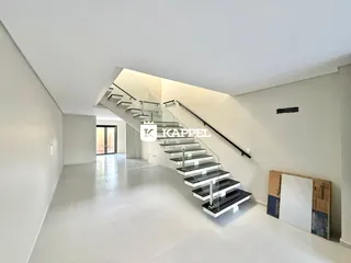 Hall de entrada com escadaria moderna e piso claro.