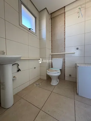 Foto de um banheiro com revestimento cerâmico branco e piso claro.