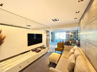 Sala de estar moderna com sofá e televisão em um ambiente claro.