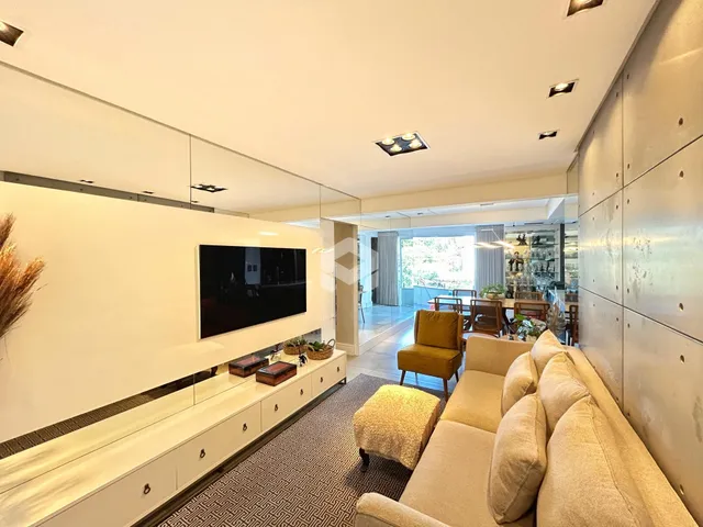 Sala de estar moderna com sofá e televisão em um ambiente claro.