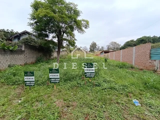 Vista externa de uma propriedade com gramado e muro de tijolos.
