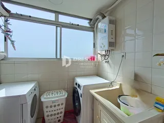 Foto de uma área de serviço com máquinas de lavar roupa e revestimento branco.