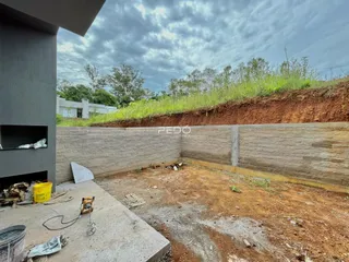 Uma parede de contenção de concreto separa uma área de terra íngreme com vegetação.