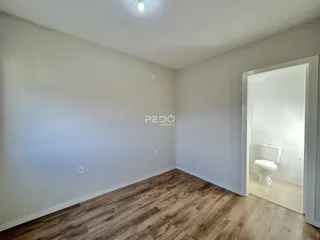 Foto de uma sala com piso de madeira clara e paredes brancas.