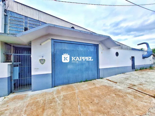 Fachada externa de um imóvel com garagem azul e muro de grade.